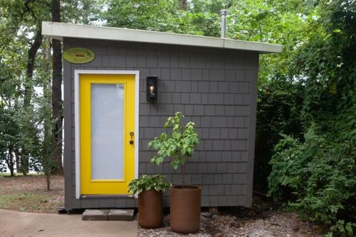 a small shed with a yellow door and a plant at Crystal Serenity Quartz Soak The Namaste Studio On Lake Hamilton in Hot Springs