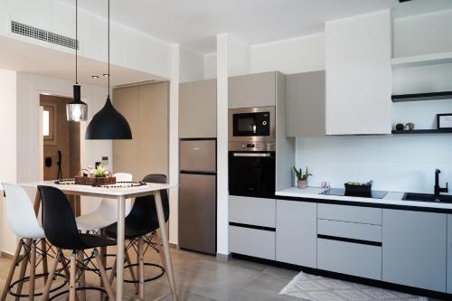 a kitchen with white cabinets and a table with chairs at Apademia Skyros Luxury Residences in Skiros