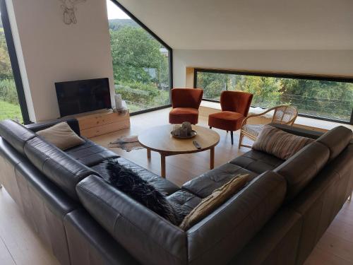 a living room with a leather couch and a table at Champs Erezée , genieten in elk seizoen in Érezée