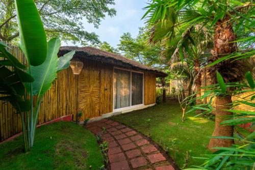 a cottage with a thatched roof and a walkway at Dandeli Wild River Resort in Dandeli