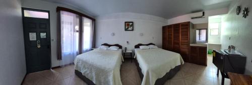 a room with two beds with white blankets and a kitchen at Hotel Divisamar by LHR in Manuel Antonio