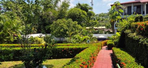 a garden with flowers and a brick walkway at Hotel Divisamar by LHR in Manuel Antonio