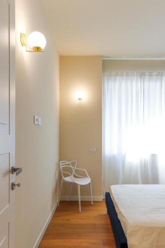 a bedroom with a bed and a chair next to a window at MilanLife Apartments - DTown Charme in Milan