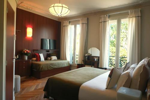 a bedroom with two beds and a large window at Hôtel d'Argenson in Paris