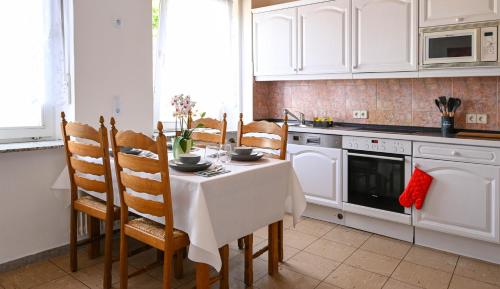 a kitchen with white cabinets and a table and chairs at Mahesars Home 2 in Ennepetal