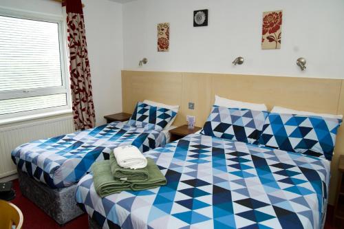 a bedroom with two beds with blue and white at The Gatwick White House Hotel in Horley