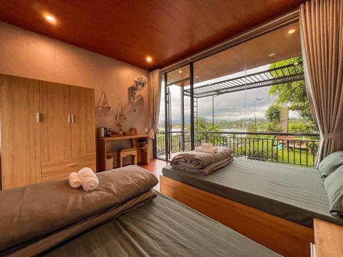 a bedroom with two beds and a large window at Ki-ss House Coffee and Glamping in Di Linh