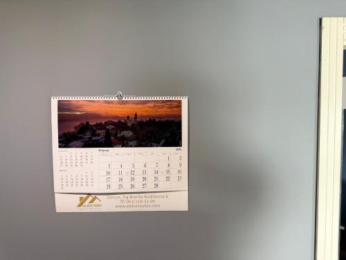 a calendar hanging on a wall with a sunset at Aleksei Apartmani in Belgrade