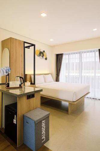 a bedroom with a bed and a desk with a phone at Alzeto Coliving in Legian