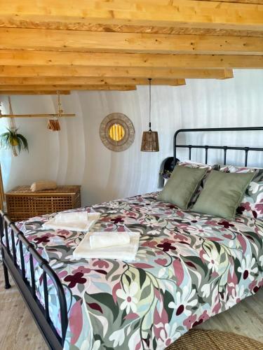 a bedroom with a bed with a floral comforter at Casinhas dos Valados in Atouguia da Baleia