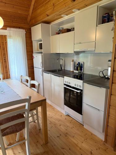 a kitchen with white appliances and a wooden table at Paritalomökki Pytkynharjussa in Syöte