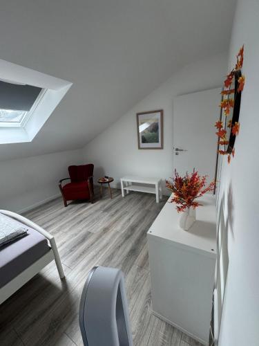 a white room with a bed and a table with flowers at Waldzauber - Moderne Ferienwohnung im Grünen in Elpenrod