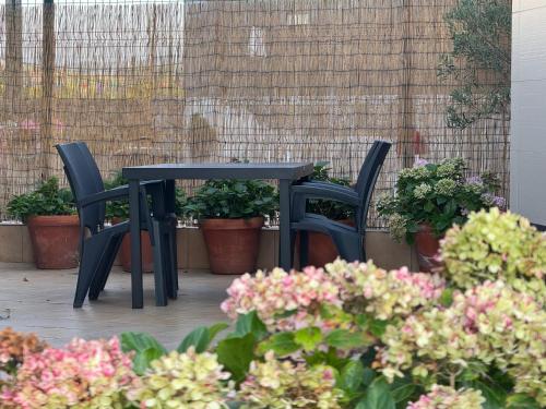 two chairs and a black table and some flowers at Apartamento Camino a Lancha in Miengo