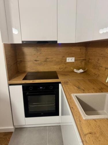 a kitchen with white cabinets and a stove and a sink at ApartmanGrandTrade by Termax in Banja Luka