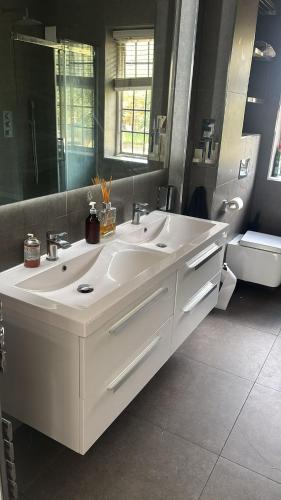 a bathroom with a white sink and a mirror at Spacious Guest House Thornton Road, London in London