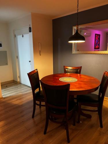 a dining room with a wooden table and chairs at Departamento de Hostal el Valle in Angol
