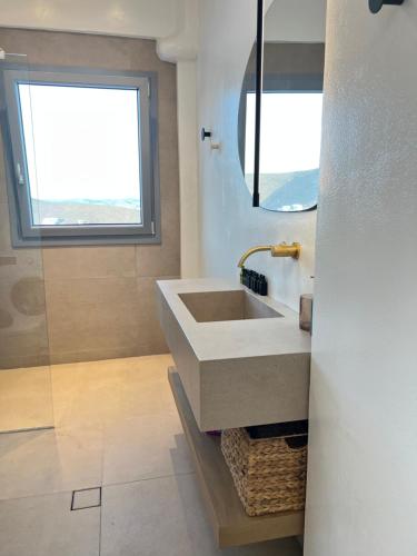 a bathroom with a sink and a window at Gerani Deluxe Houses 2 in Astypalaia Town
