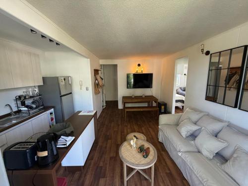 a living room with a white couch and a kitchen at Departamento familiar en Pucón in Pucón