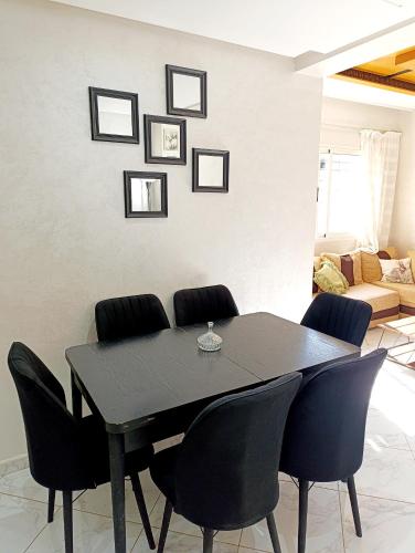 a black dining room table with black chairs in a living room at Sala Al Jadida - Appartement meublé à 5 min de Technopolis et 13 min de l'aéroport in Oulad Yakoub