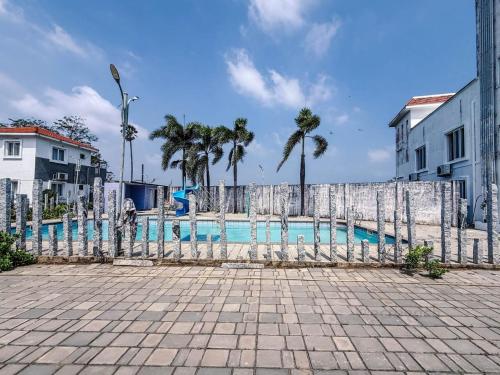 a fence next to a swimming pool with palm trees at Hotel Manjula INN in Mahabalipuram