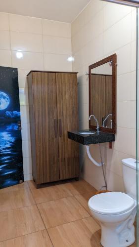 a bathroom with a toilet and a sink and a mirror at Pousada Rancho Dona Lú Comfort in Pereira Barreto