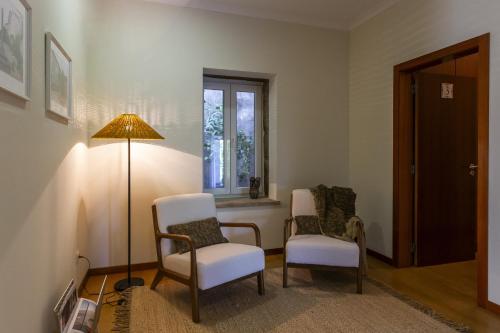 a room with two chairs and a lamp and a window at Casa da Câmara in Tondela