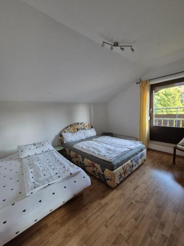 zwei Betten in einem Zimmer mit Fenster in der Unterkunft Charmanter Rückzugsort im DG in Lindenberg im Allgäu