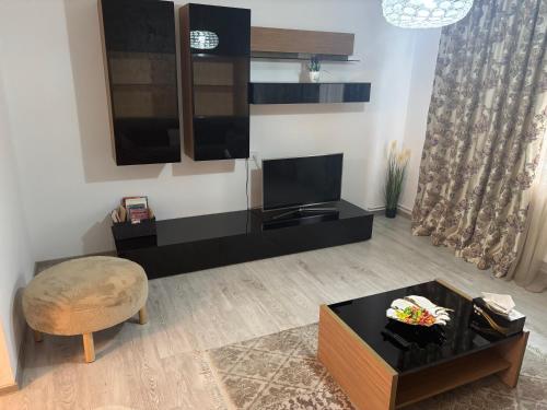 a living room with a tv and a chair and a table at Apartament SUN Drăgășani in Drăgăşani