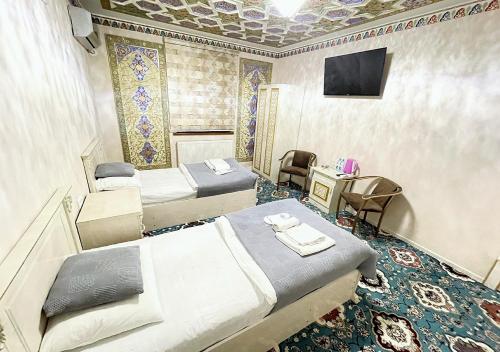Una habitación con dos camas y un televisor. en Faxriddin East Hotel, en Bukhara