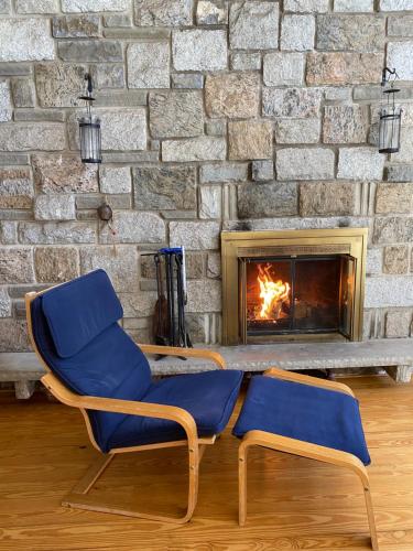 two blue chairs in front of a brick fireplace at Secluded Chalet On Stream-Mins to Camelback in Tannersville