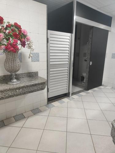 a bathroom with a vase of flowers on a tile floor at Nova Jerusalém in Cianorte