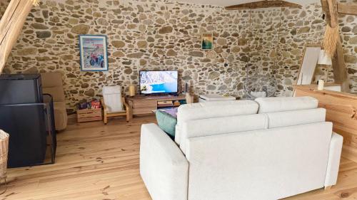 a living room with a white couch and a tv at Le Refuge du Cagire in Aspet