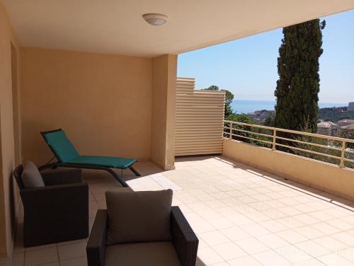 a balcony with a green chair and a couch at T2 vue panoramique mer montagne in Cardo
