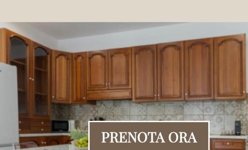a kitchen with wooden cabinets with the words premoria ore at Nino's House in Sperlinga