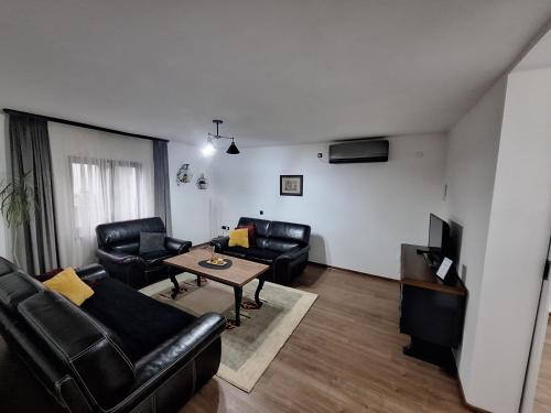a living room with black leather furniture and a tv at Apartman Eterna in Bijeljina