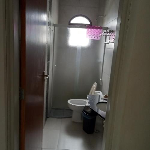 a bathroom with a toilet and a sink and a window at Pousada Parque Suites - Estacionamento e Piscina in Guarujá