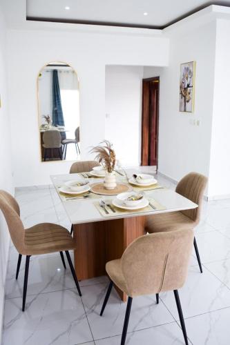 a dining room with a white table and chairs at Appartement Grenoble in Yaoundé