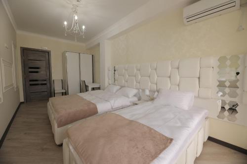 a white bedroom with two beds and a chandelier at Hotel Harmony Premium in Kutaisi
