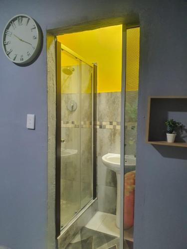 a bathroom with a shower and a clock on the wall at Stofberg Guest House in Brits
