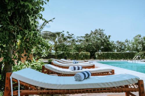 a row of lounge chairs next to a swimming pool at Balungi Boutique Hotel in Uroa