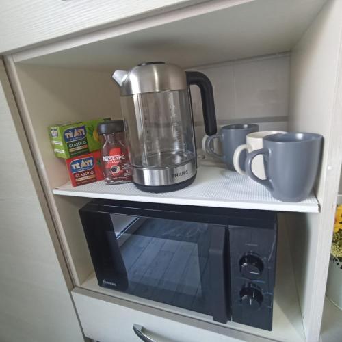 a coffee maker and cups sitting on top of a microwave at Casa Mole, Roma in Marino
