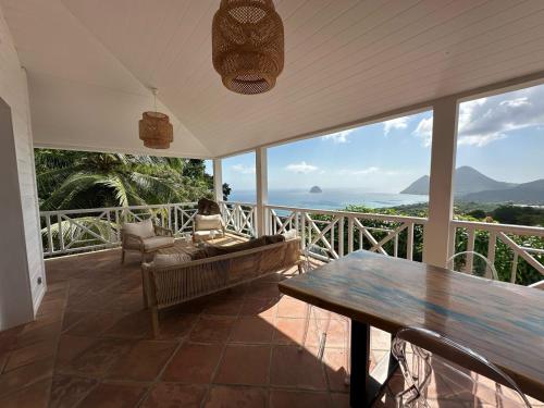 a living room with a table and a view of the ocean at Villa Clémentine in Le Diamant