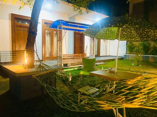 a hammock with a table and an umbrella at Sahan Tourist House in Polonnaruwa