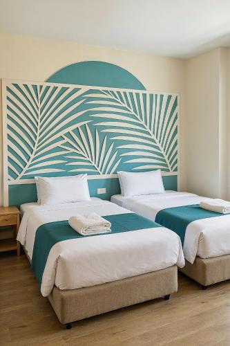 two beds in a room with a painting on the wall at Kue Hotel Maafushi in Maafushi