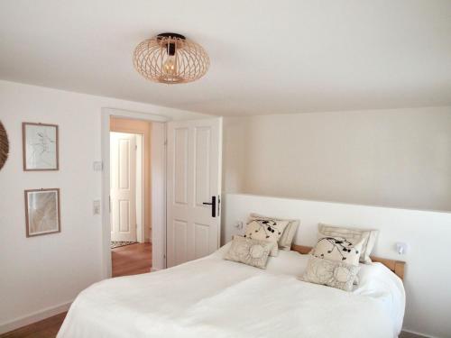 a bedroom with a white bed and a chandelier at Kleines Landhaus von 1870 in Ruppichteroth