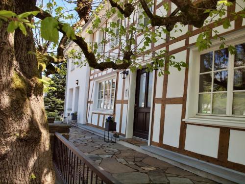a tree in front of a house with a fence at Kleines Landhaus von 1870 in Ruppichteroth