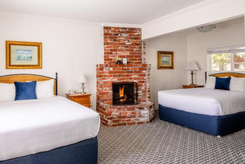 two beds in a room with a fireplace at Carmel Fireplace Inn in Carmel