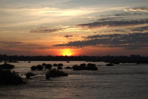 a sunset over a river with the sun setting at Don Som Riverside Guesthouse in Don Som