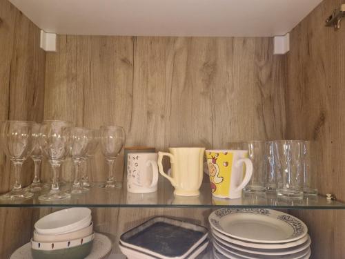 a glass shelf with dishes and glasses on it at Lovely Home by the Beach in Kruče
