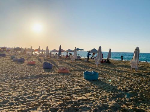 a beach with umbrellas and chairs and the ocean at شاليه بقريه جرين بيتش الساحل الشمالي 4 غرف تشطيب السنه لوكس in El Alamein